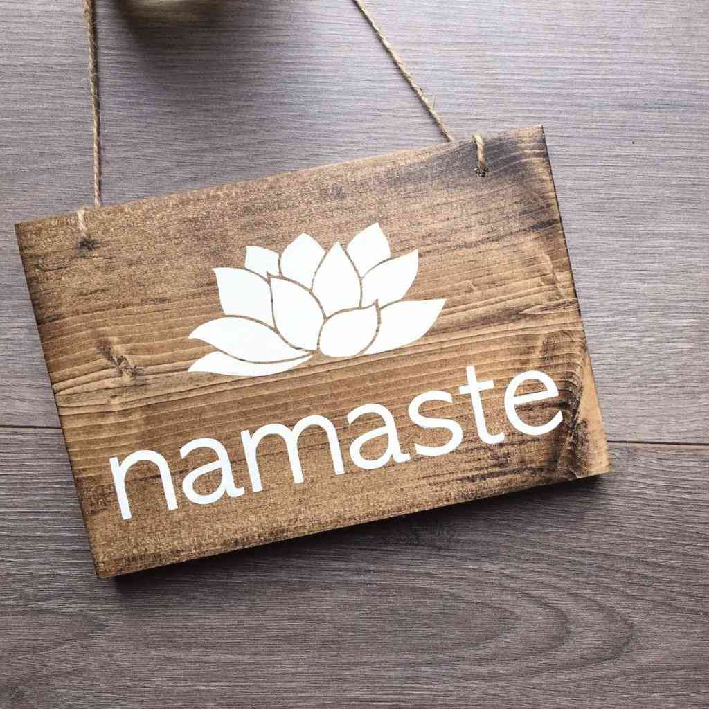Kleine Namaste mit Blumen hängendem Holzschild